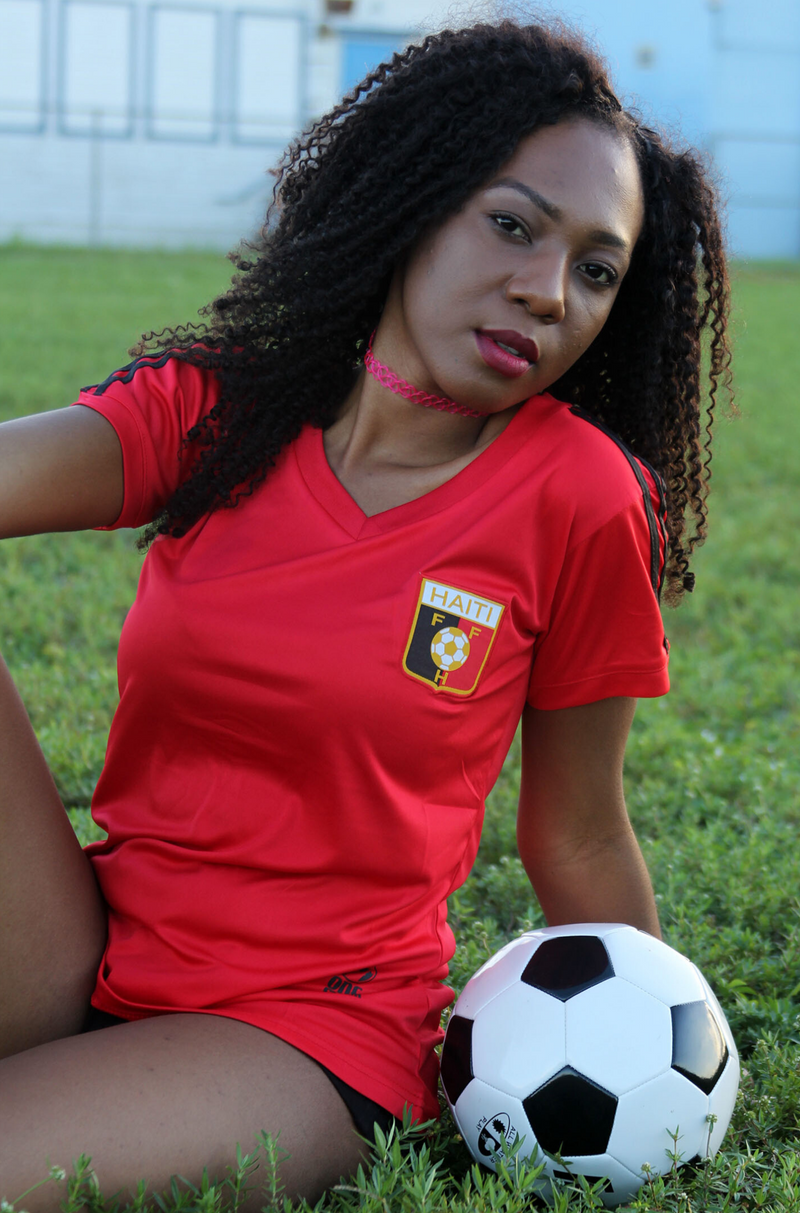 One Flag Nation™ Haitian Pride Black and Red Official Sport Jersey Woman Sitting with Soccer Ball 2